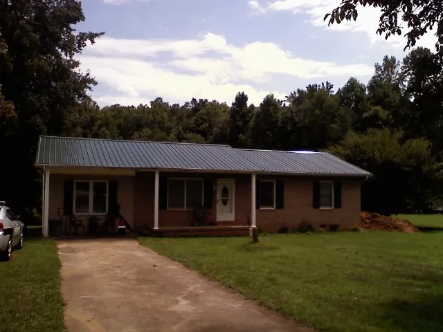 Dark green metal roof on a brick ranch with a covered porch in Jefferson