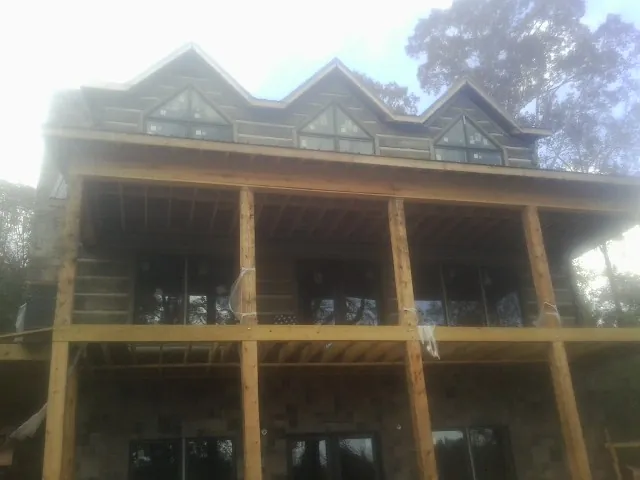 Dormers and porch framing on a large log home under construction — Roof Coating work by our crew in Jefferson